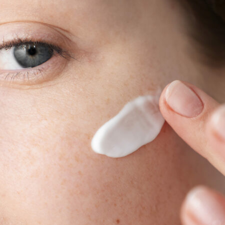 Donna si spalma la crema solare viso